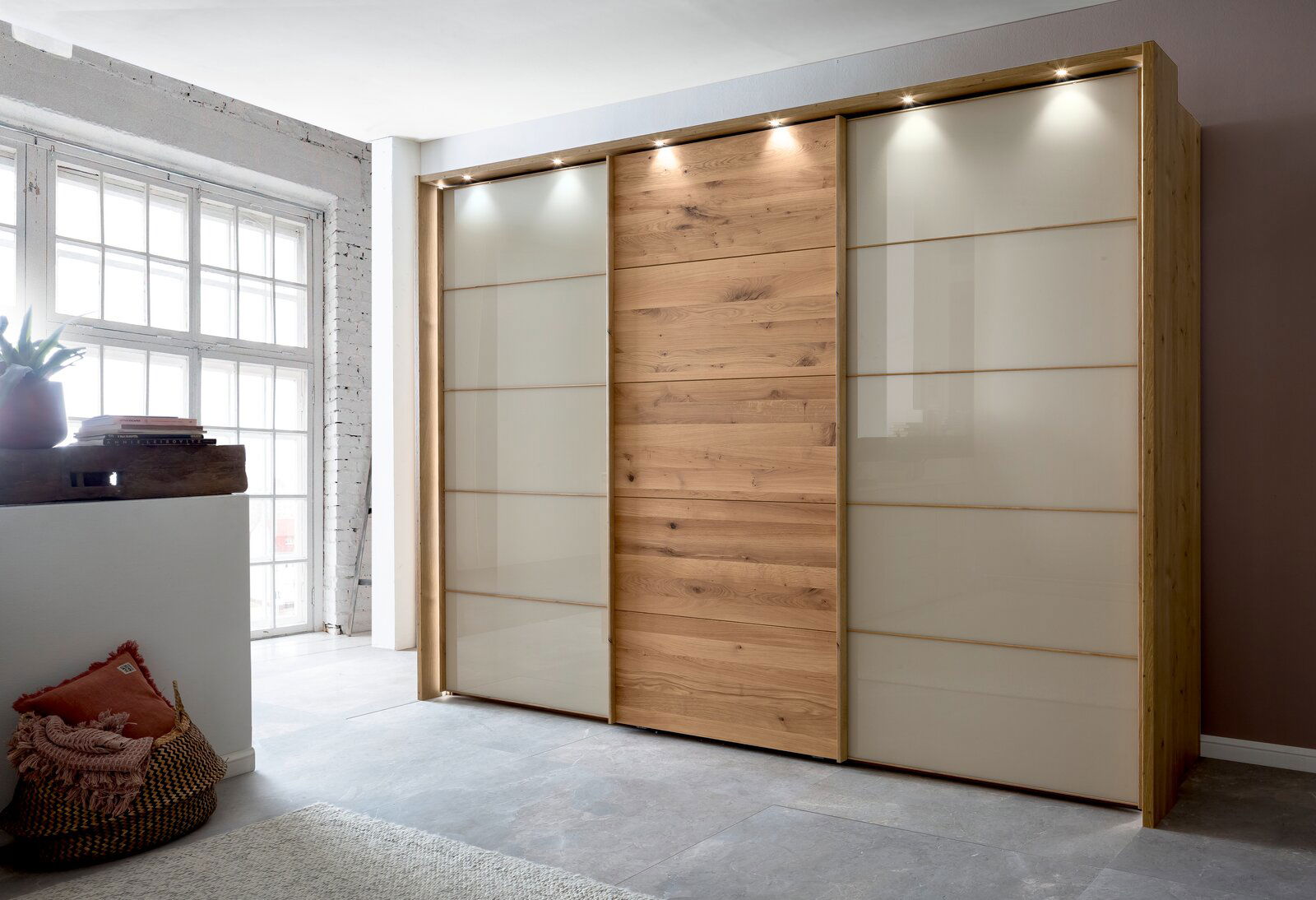 Moderner dreitüriger Schwebetürenschrank aus Holz und Glas mit integrierter Beleuchtung, seitliche Perspektive