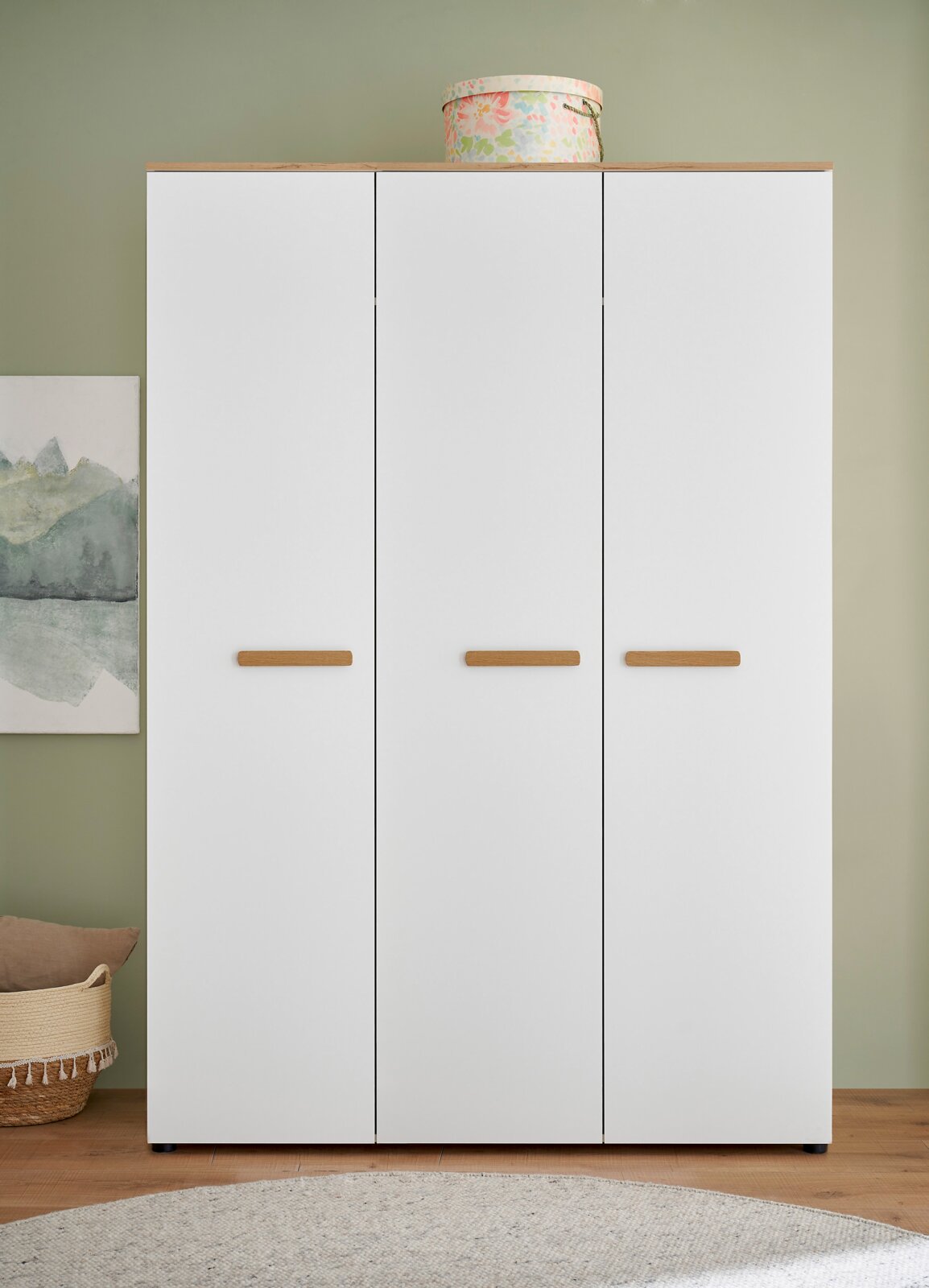 Weißer dreitüriger Kleiderschrank mit Holzoptik-Abdeckplatte und horizontalen Holzgriffen, frontal aus der Vorderansicht fotografiert.