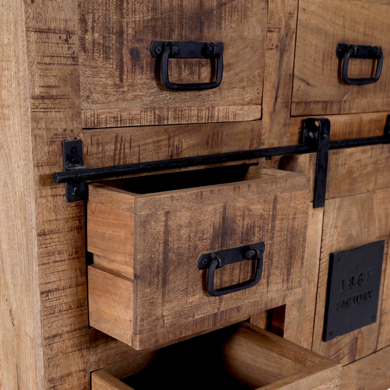 Close-up van een rustiek houten secretaire met zwarte metalen handgrepen en lades, gedeeltelijk geopend, gezien vanuit de zijkant.