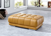 XXL-Hocker in hellbraunem Leder, seitliche Perspektive, in modernem Wohnzimmer mit großen Fenstern.
