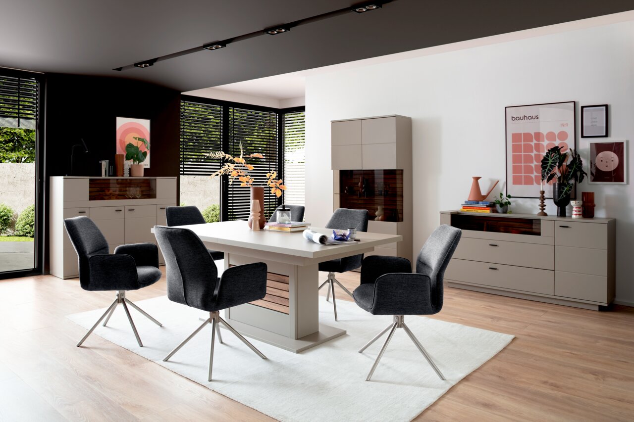 Moderne Esszimmer-Einrichtung mit Esstisch, Stühlen und Vitrinen in einem hellen Raum, seitliche Perspektive.