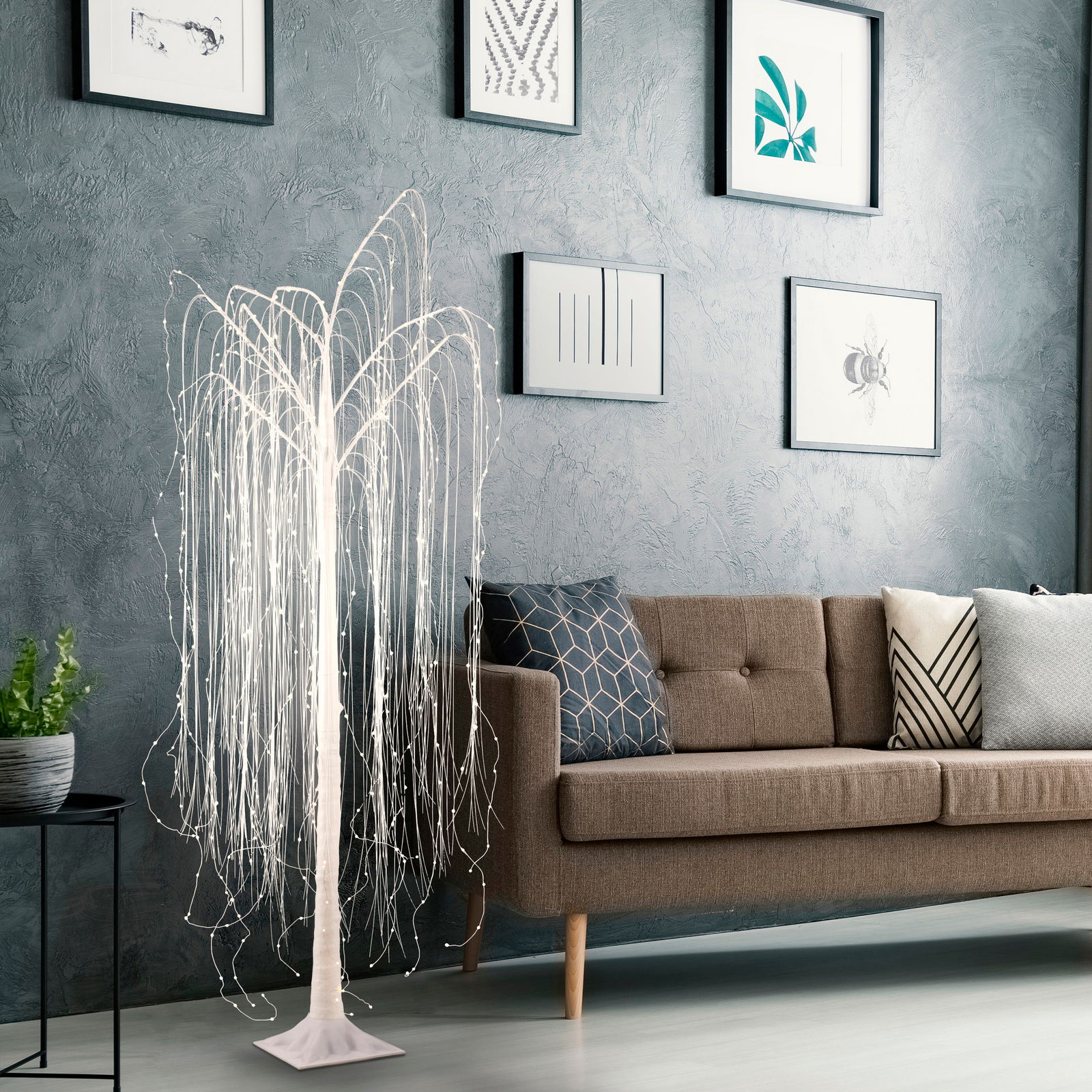 LED-Baum in Weiß, WILLOW, in einem modernen Wohnzimmer neben einem Sofa, aus seitlicher Perspektive fotografiert.