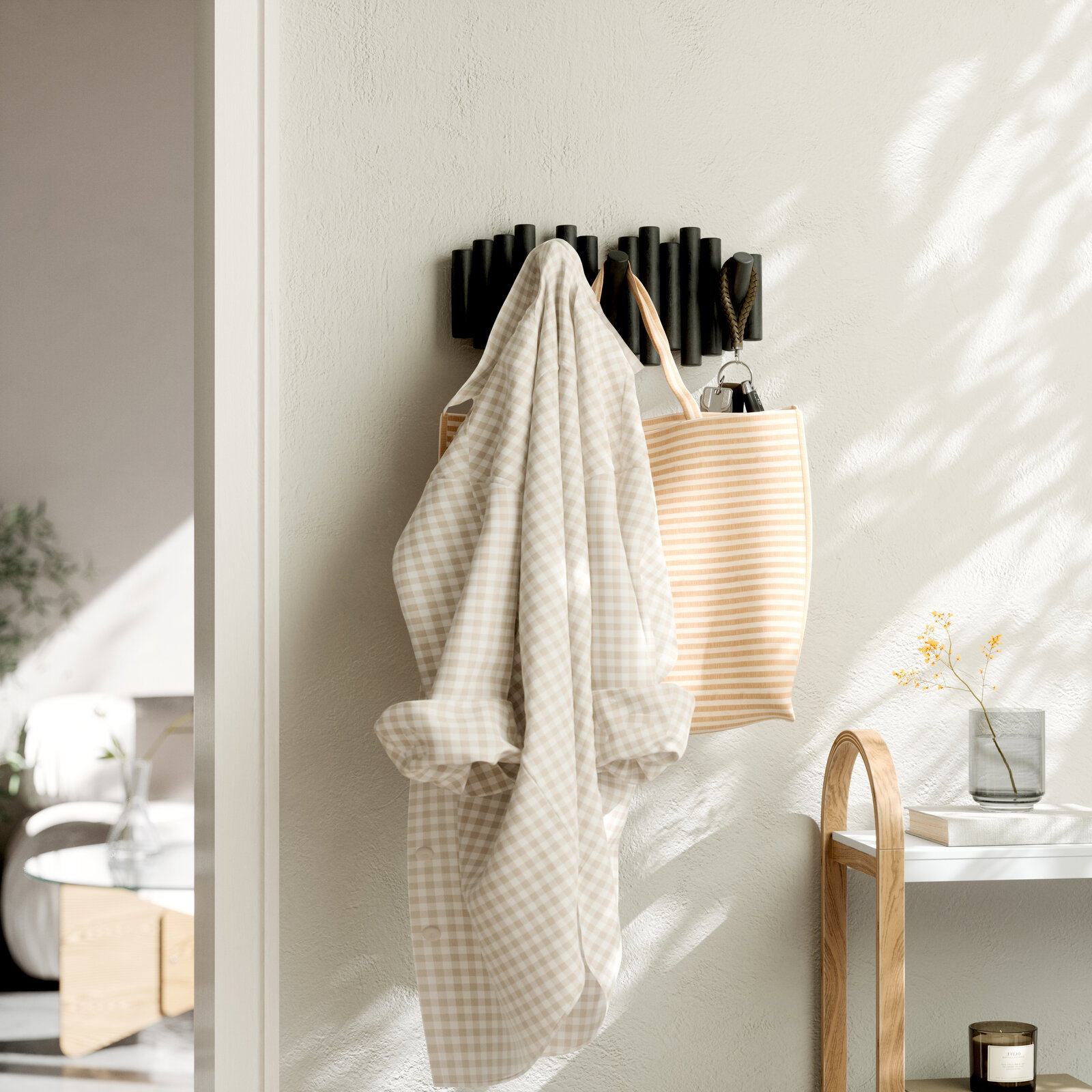 Wandgarderobe mit mehreren Haken, an der ein kariertes Hemd und eine gestreifte Tasche hängen, seitliche Perspektive