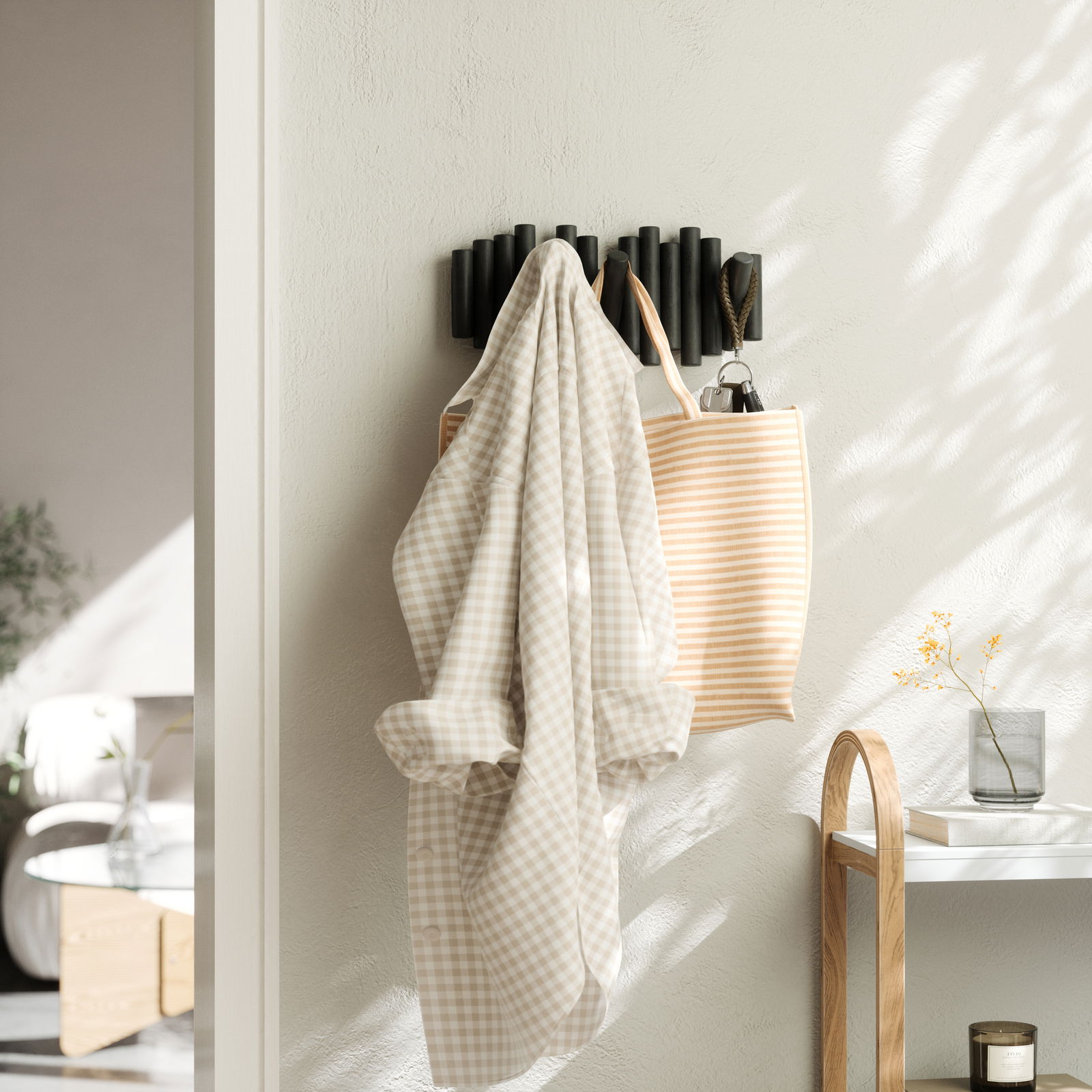 Wandgarderobe mit mehreren Haken, an der ein kariertes Hemd und eine gestreifte Tasche hängen, seitliche Perspektive