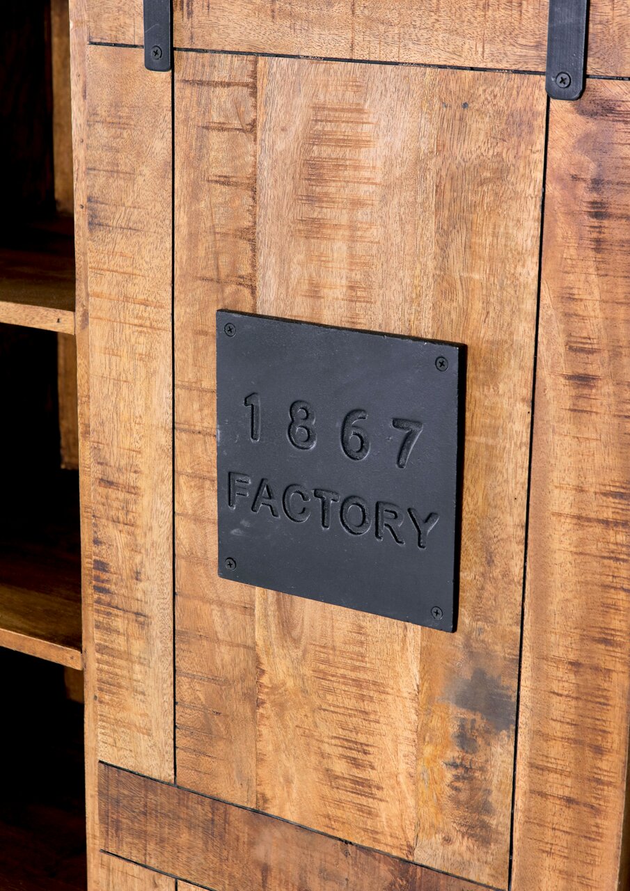 Nahaufnahme eines rustikalen Highboards aus Holz mit schwarzem Metallschild, das die Aufschrift '1867 FACTORY' trägt. Perspektive von schräg vorne.