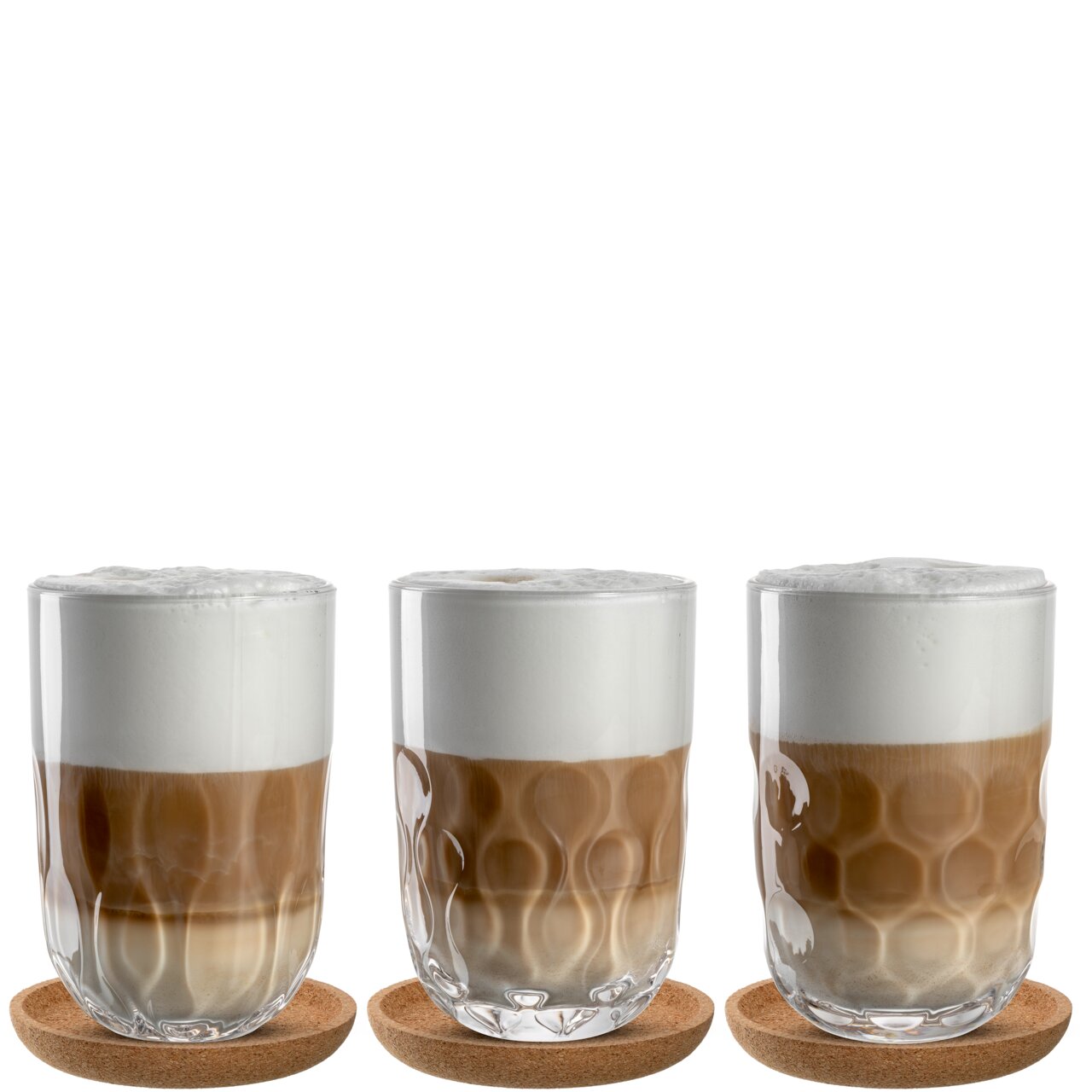 Drei Latte Macchiato-Gläser mit Schaumkrone auf Korkuntersetzern, frontal fotografiert.