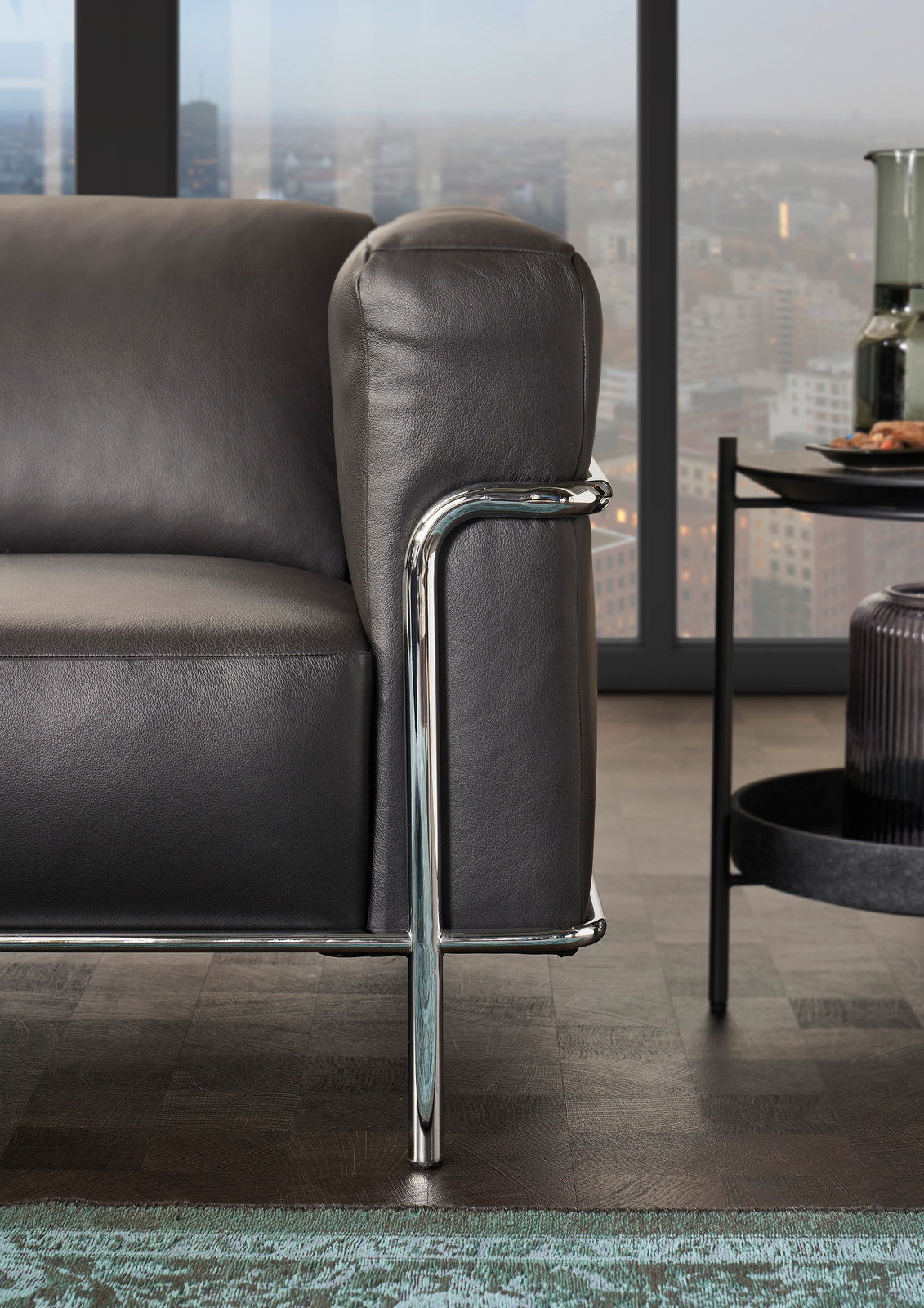 Nahaufnahme eines modernen Sofas mit schwarzem Lederbezug und verchromtem Metallrahmen, seitliche Perspektive.