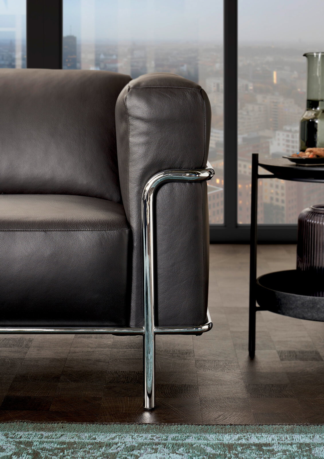 Nahaufnahme eines modernen Sofas mit schwarzem Lederbezug und verchromtem Metallrahmen, seitliche Perspektive.