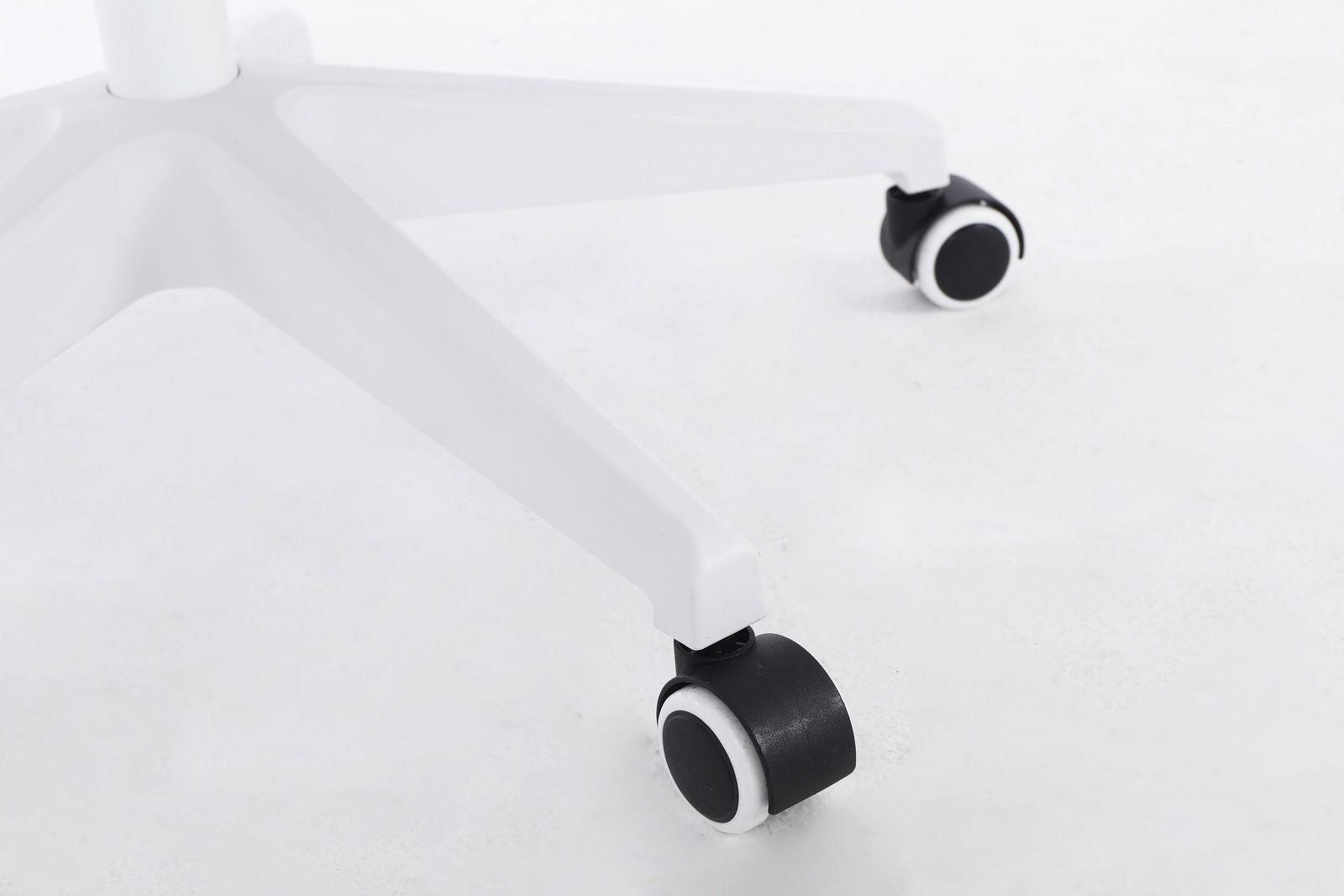 Nahaufnahme der weißen Basis eines Drehstuhls mit schwarzen Rollen, von der Seite betrachtet.