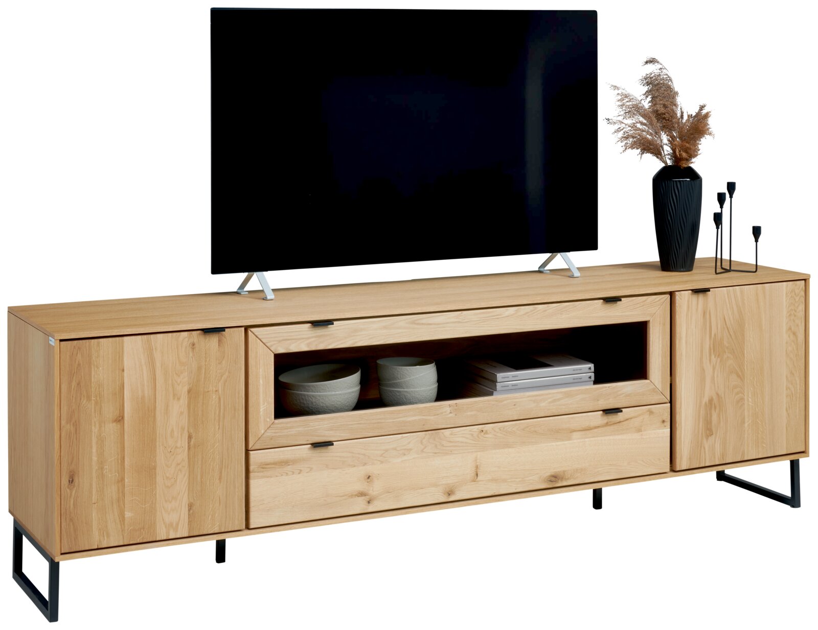 Houten tv-meubel in licht eikenlook met twee kastdeuren, open vak en lade op zwart metalen onderstel, frontaal aanzicht met tv en decoratie erop