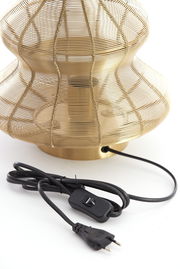Nahaufnahme einer Tischleuchte mit einem goldenen, drahtgeflechtartigen Schirm und einem schwarzen Kabel mit Schalter.