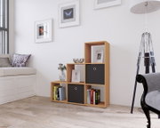 Modernes Stufenregal in heller Holzoptik mit offenen Fächern und zwei schwarzen Boxeinsätzen, dekoriert mit Büchern, Vase und Bilderrahmen, im Wohnzimmer – frontale Ansicht mit leichter Perspektive von links.