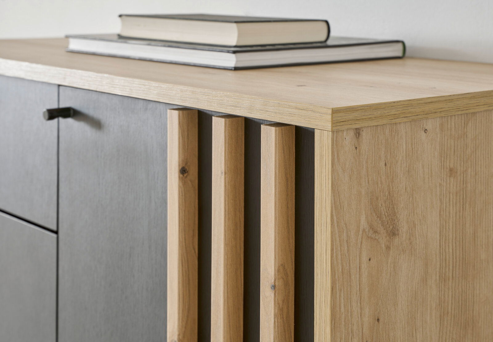 Nahaufnahme eines Garderobenschranks aus Holz mit grauen Türen und dekorativen Holzleisten, seitliche Perspektive