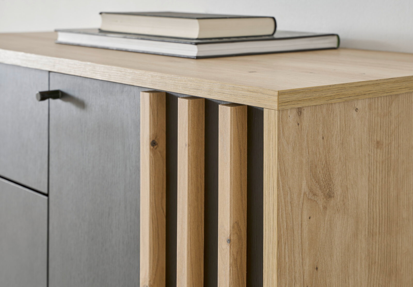Nahaufnahme eines Garderobenschranks aus Holz mit grauen Türen und dekorativen Holzleisten, seitliche Perspektive