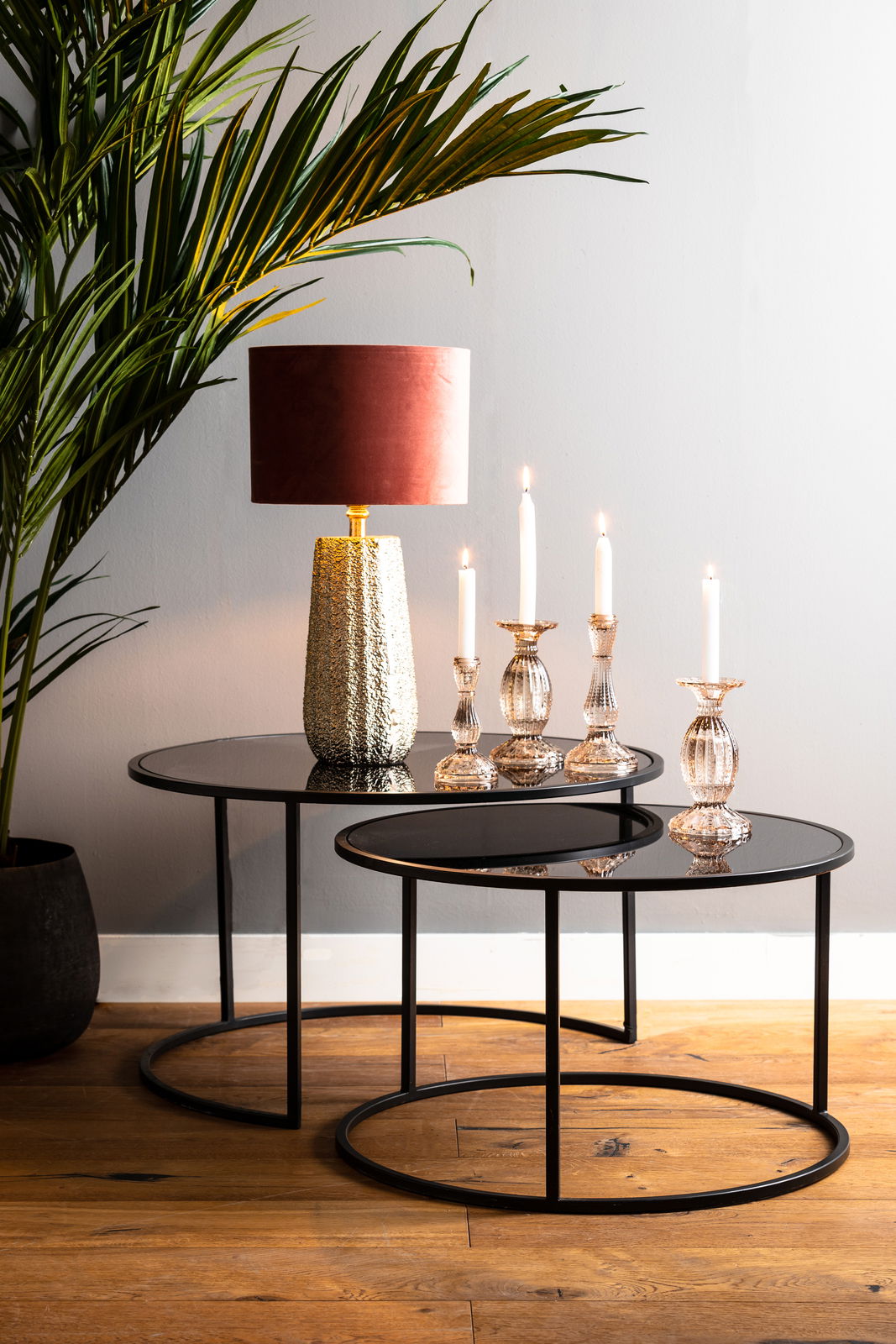 Light&Living Couchtisch-Set DUARTE Zwei runde Couchtische in verschiedenen Größen mit schwarzer Glasplatte und Metallrahmen, dekoriert mit einer Tischlampe und Kerzenhaltern, aus seitlicher Perspektive fotografiert.