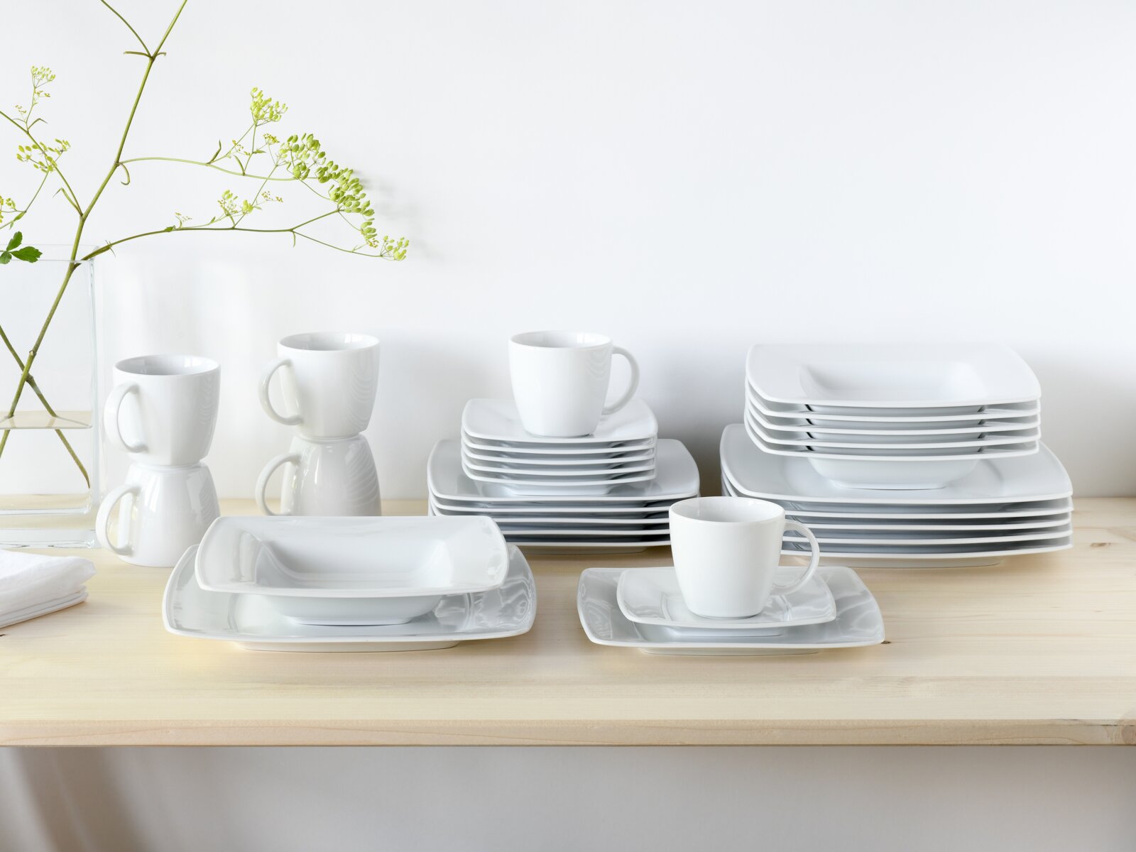 Creatable Kombiservice 30-tlg VICTORIA Weißes Porzellan-Geschirrset mit stapelbaren rechteckigen Tellern/Platten und Kaffeetassen auf hellem Holztisch vor weißer Wand, perspektivisch in leichter Schrägansicht von vorne.