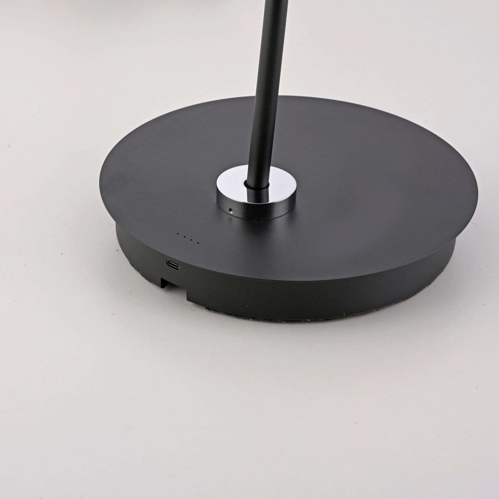 Nahaufnahme der Basis einer schwarzen Akku-Stehleuchte mit USB-Anschluss und Ladeanzeige.