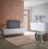 Modernes TV-Hängelowboard in Weiß, frontal betrachtet, montiert an einer Wand mit Marmoroptik, neben einem großen Fenster.