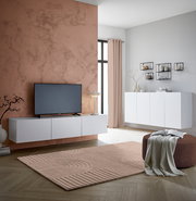 Modernes TV-Hängelowboard in Weiß, frontal betrachtet, montiert an einer Wand mit Marmoroptik, neben einem großen Fenster.