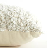 Nahaufnahme eines Kissens mit bouclé Textur in Cremeweiß, seitliche Perspektive