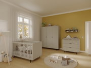 Kinderzimmer mit einem modernen, grauen Kinderbett in der linken Bildhälfte, umgeben von einem Kleiderschrank und einer Wickelkommode, aus der Perspektive eines Betrachters, der den Raum betritt.