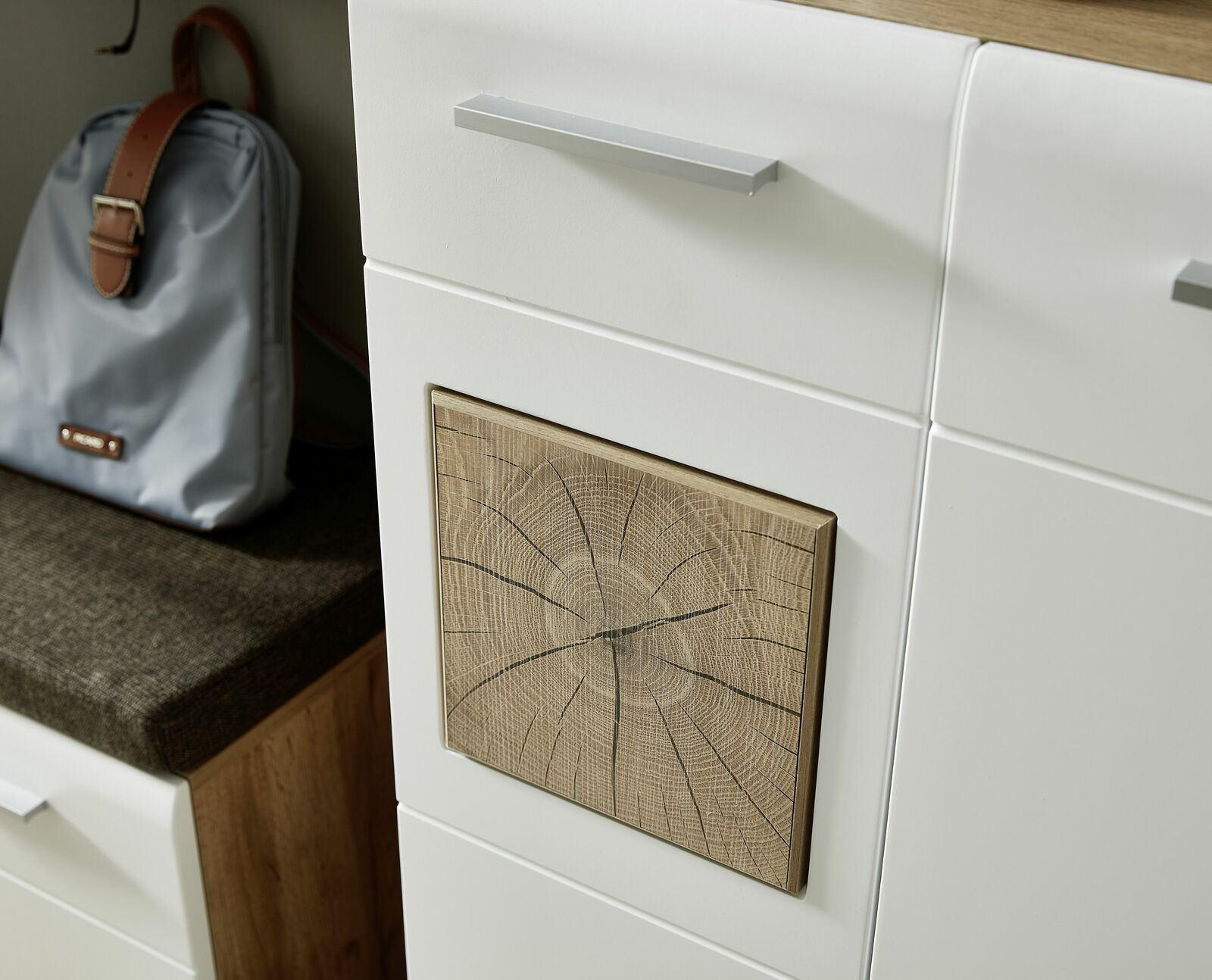 Nahaufnahme eines Garderoben-Sets mit weißem Schrank und Holzdekor-Element, seitliche Perspektive.