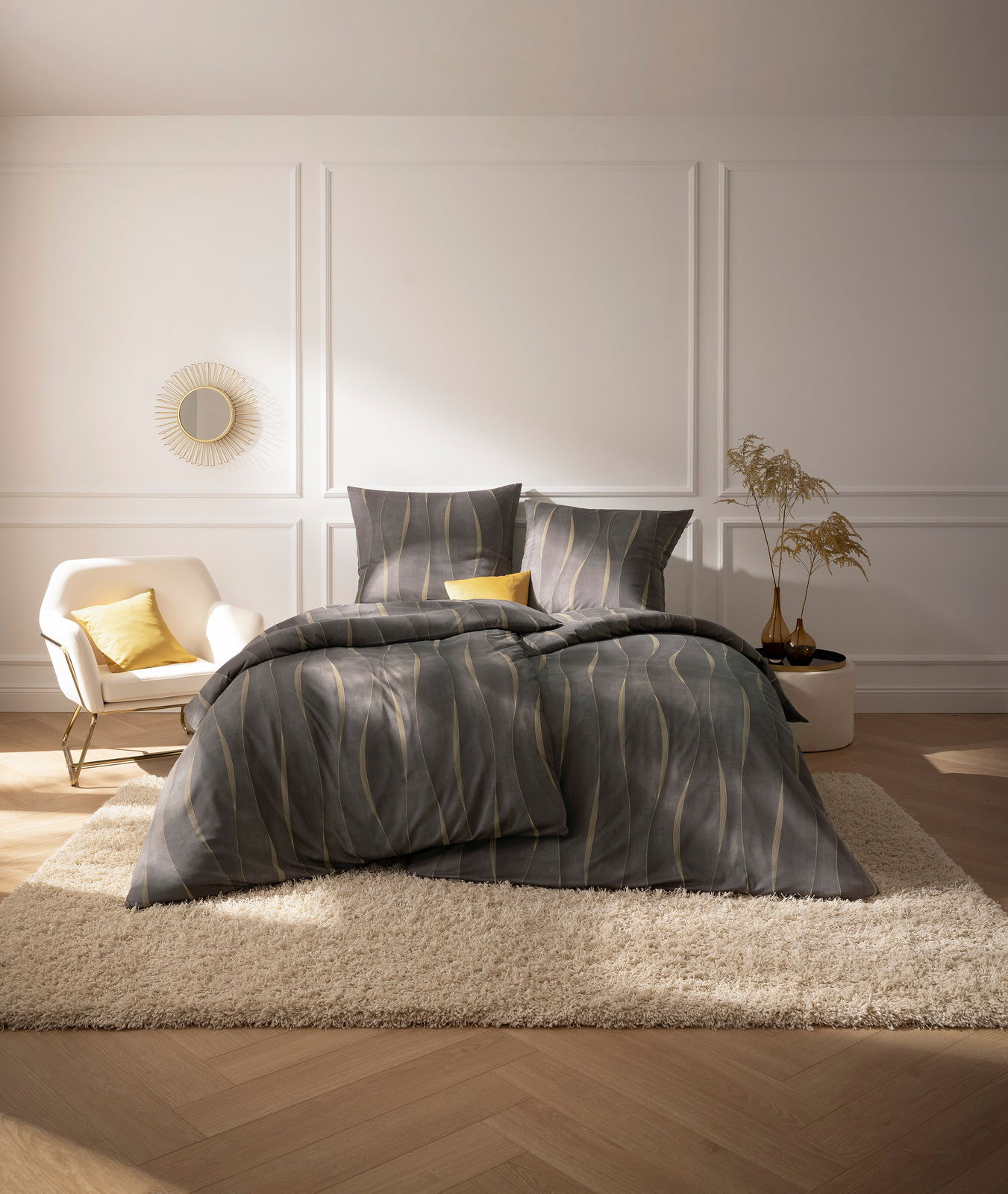 Blick auf ein stilvoll eingerichtetes Schlafzimmer mit Estella Bettwäsche CAJA in Grau und Gelb auf einem Bett, umgeben von eleganter Dekoration.
