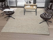 Handgewebter Teppich in einem modernen Wohnzimmer mit braunen Ledersesseln und einem Couchtisch, aus der Vogelperspektive betrachtet.