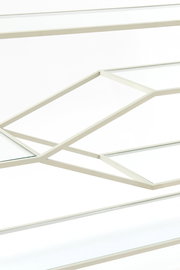 Nahaufnahme eines Konsolentisches mit geometrischem Metallrahmen und Glasplatten, seitliche Perspektive