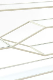 Nahaufnahme eines Konsolentisches mit geometrischem Metallrahmen und Glasplatten, seitliche Perspektive