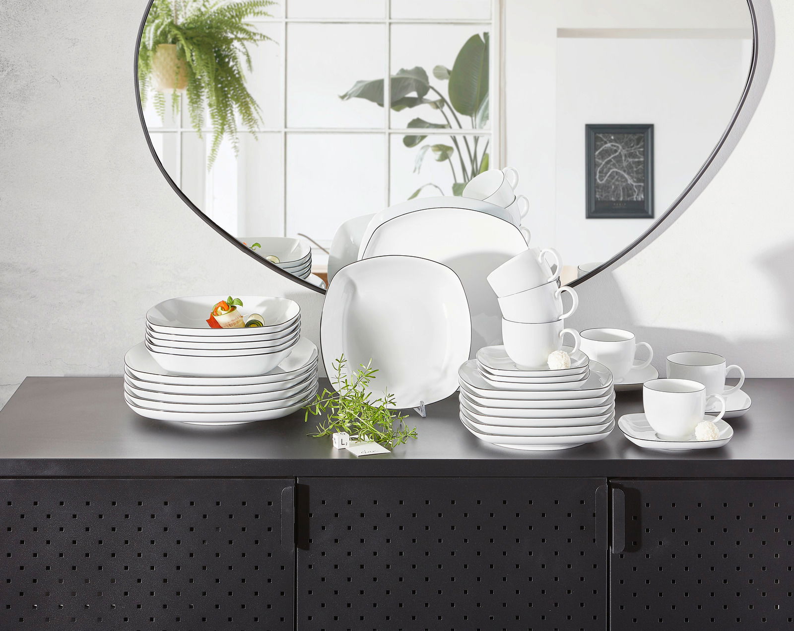 Kombiservice Lido Black eckig auf einem schwarzen Schrank, mit einem Spiegel im Hintergrund, der das Geschirr aus einer frontalen Perspektive zeigt.