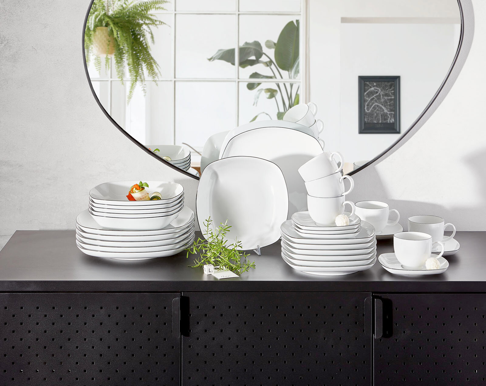 Kombiservice Lido Black eckig auf einem schwarzen Schrank, mit einem Spiegel im Hintergrund, der das Geschirr aus einer frontalen Perspektive zeigt.