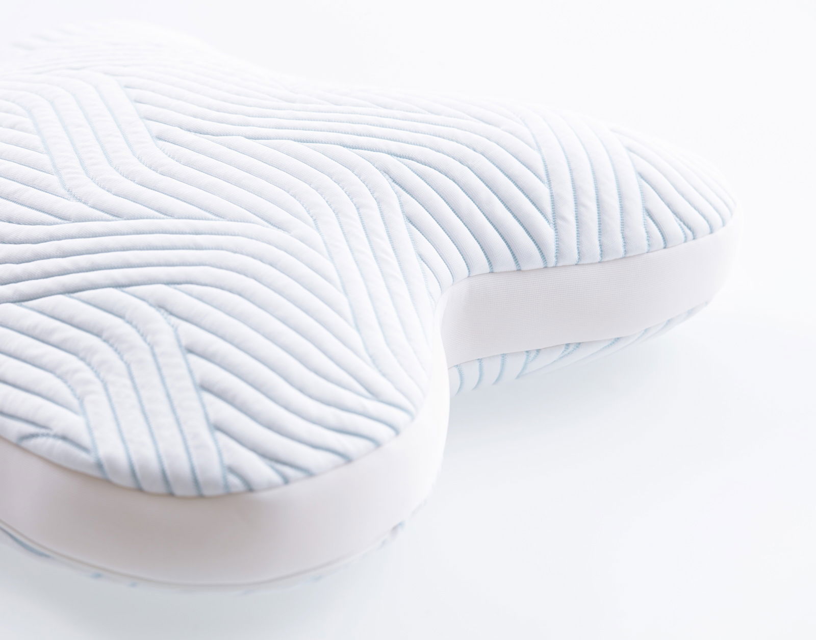 Nahaufnahme eines ergonomischen Schlafkissens mit wellenförmigem Muster, perspektivisch von der Seite aufgenommen.