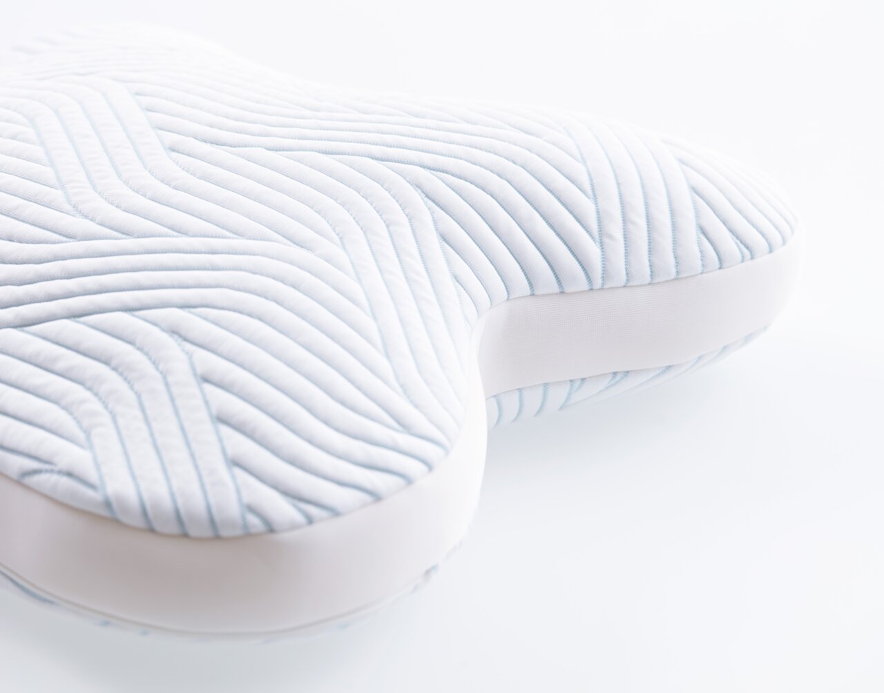 Nahaufnahme eines ergonomischen Schlafkissens mit wellenförmigem Muster, perspektivisch von der Seite aufgenommen.