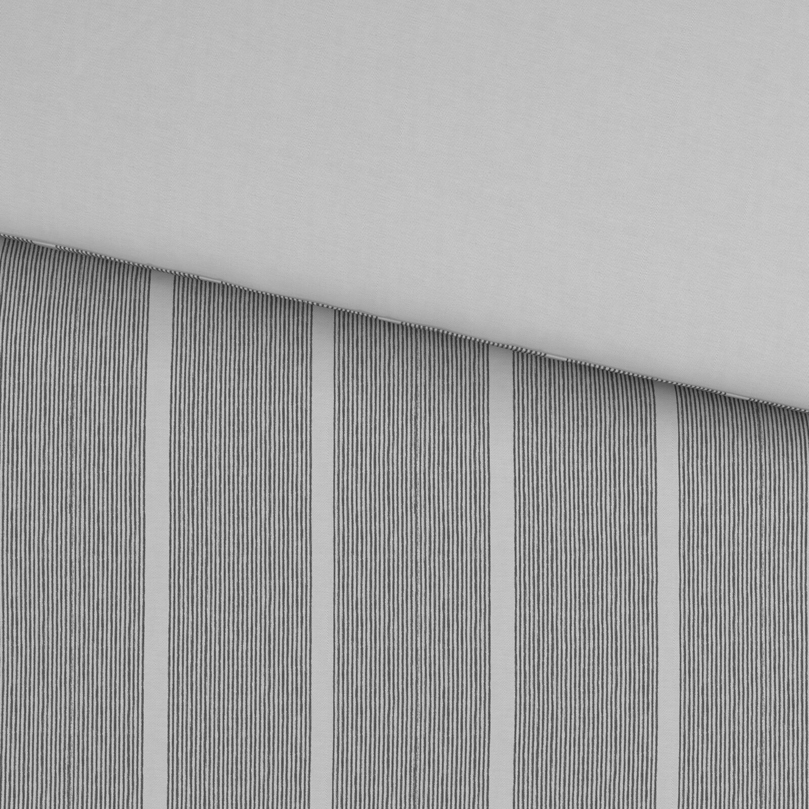 Detailaufnahme aus schräger Draufsicht: grauer Stoff mit feinen, vertikalen Streifen und sichtbarer Kante/Naht vor hellem Hintergrund