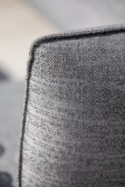 Nahaufnahme der Ecke eines grauen Loungesessels mit texturierter Stoffoberfläche.