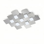 Moderne Deckenleuchte aus gebürstetem Metall mit geometrisch überlappenden Quadraten und sieben weißen Leuchtflächen, aus schräger Untersicht vor weißem Hintergrund