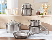 Topfset Brillant 6-tlg. aus Edelstahl, bestehend aus mehreren Töpfen und einer Pfanne mit Glasdeckeln, auf einem Tisch in einer hellen Küche präsentiert. Perspektive: seitlich.