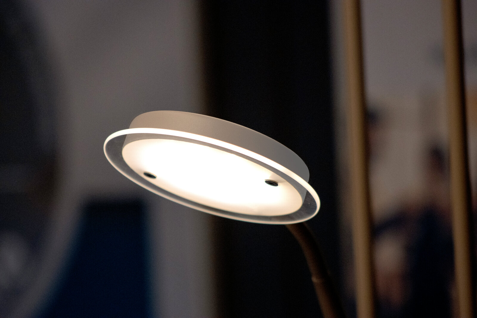 Moderne runde LED-Lampe mit weißem Diffusor und transparentem Rand, eingeschaltet, in Nahaufnahme aus schräger Seitenansicht von unten