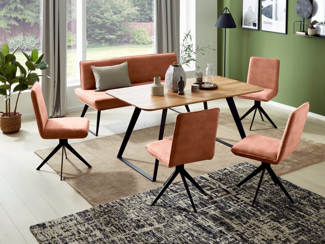 Esszimmer mit moderner Einrichtung, bestehend aus einem Holztisch, einer gepolsterten Bank und vier passenden Stühlen in warmen Erdtönen. Die Perspektive zeigt den Raum von schräg oben, mit Blick auf die gesamte Sitzgruppe und die dekorative Umgebung.