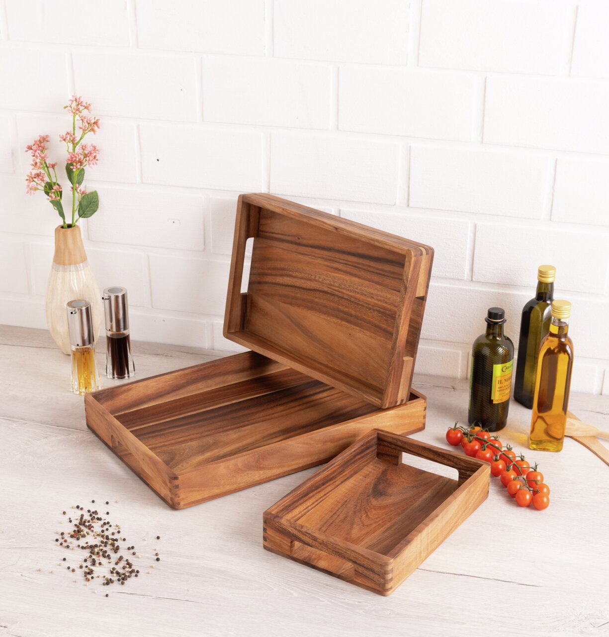Holztablett-Set in verschiedenen Größen, präsentiert auf einem Tisch mit Gewürzen und Ölen, aus seitlicher Perspektive.
