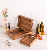 Holztablett-Set in verschiedenen Größen, präsentiert auf einem Tisch mit Gewürzen und Ölen, aus seitlicher Perspektive.