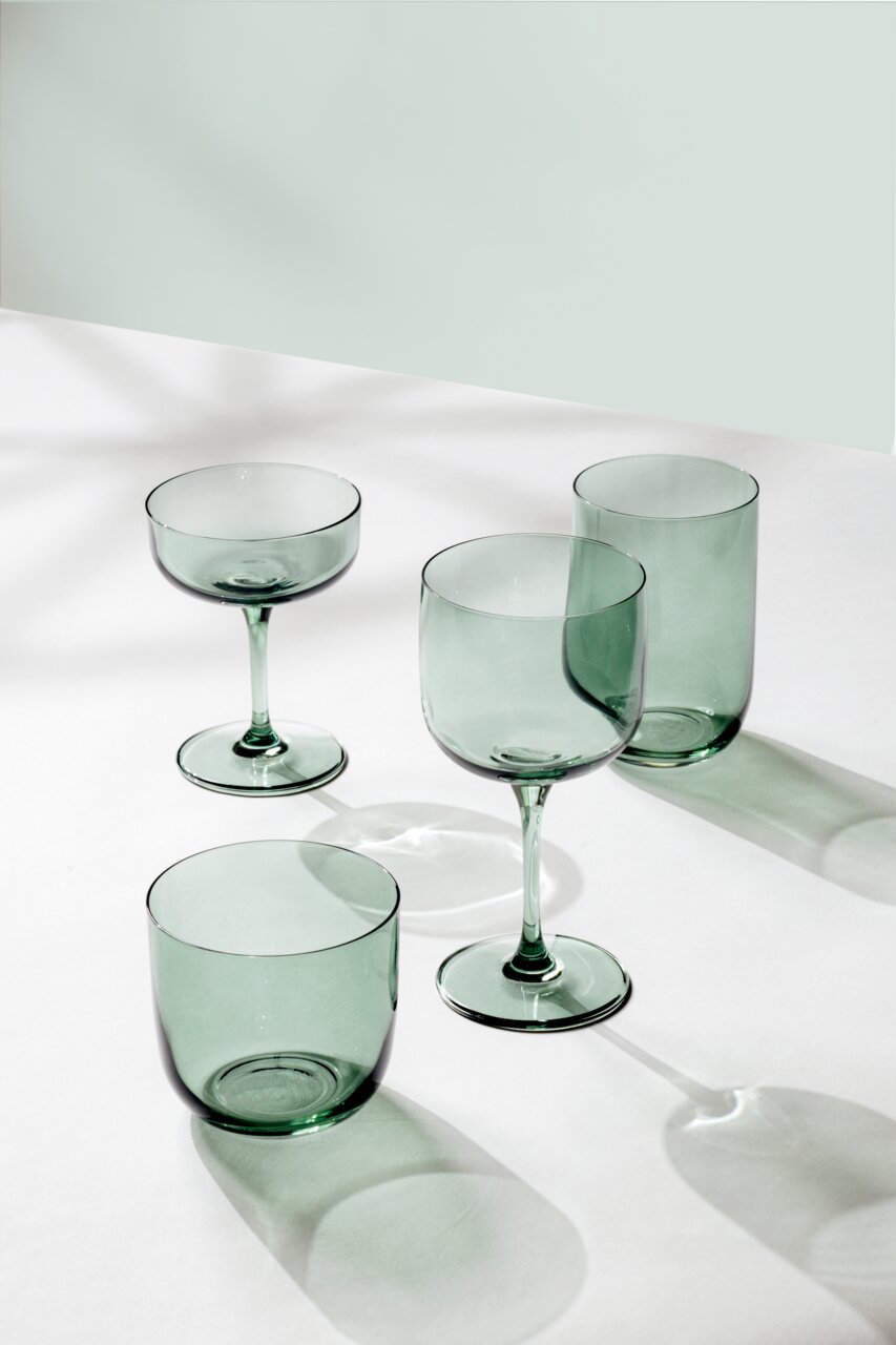 Set aus vier grünen Gläsern, bestehend aus zwei Longdrinkgläsern und zwei Weingläsern, auf einer weißen Oberfläche aus der Vogelperspektive fotografiert.