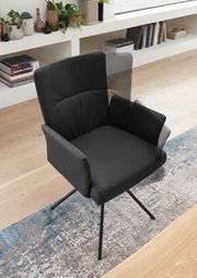 Schwarzer Sessel mit Armlehnen und Metallbeinen, von oben fotografiert, auf einem gemusterten Teppich stehend.