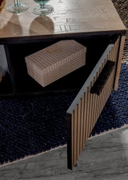 Nahaufnahme eines Couchtisches mit geöffneter Tür, die einen Stauraum mit einer dekorativen Box zeigt. Die Tischoberfläche ist aus Holz mit Glasdekorationen. Perspektive von oben.