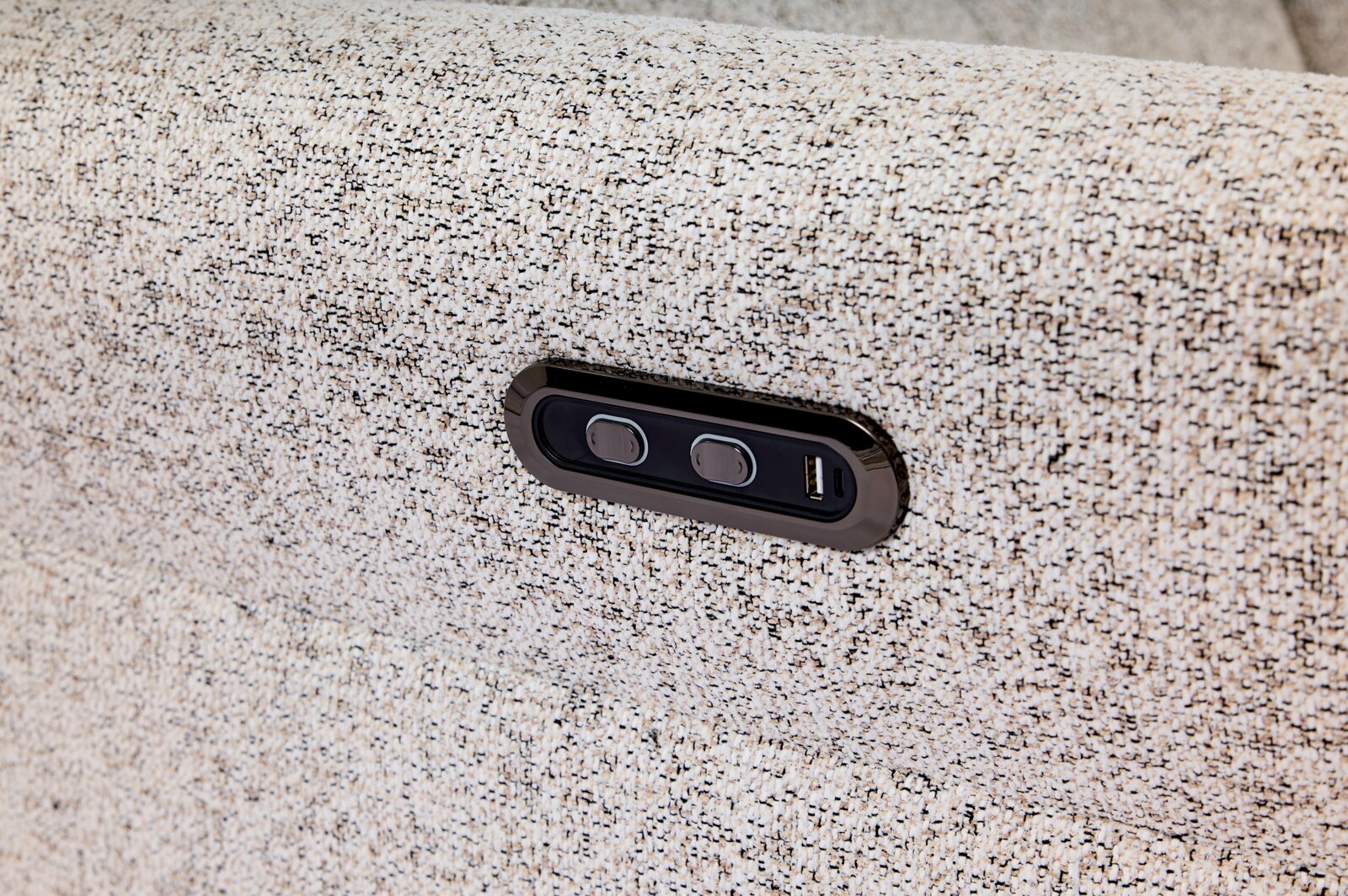Nahaufnahme einer strukturierten Stoffoberfläche mit integrierter Bedieneinheit und USB-Anschluss, seitliche Perspektive.