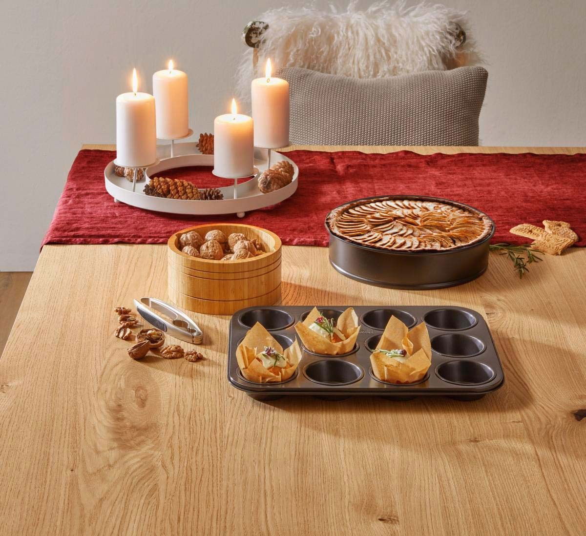 Muffin-Blech mit 12 Vertiefungen, teilweise mit Muffins gefüllt, auf einem Tisch aus Holz, aus der Vogelperspektive fotografiert.