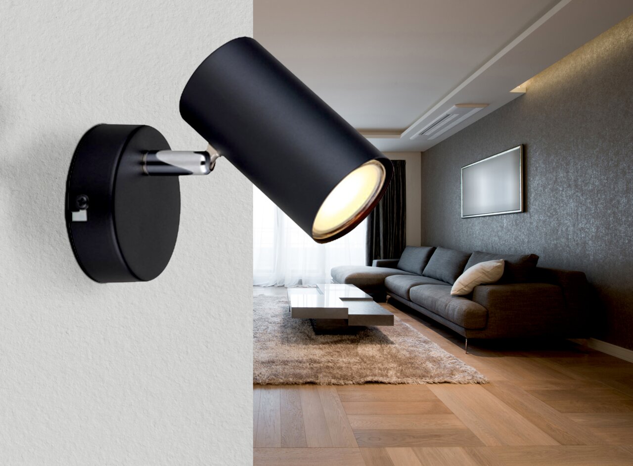 Een moderne zwarte spot, aan de muur bevestigd, verlicht een stijlvolle woonkamer vanuit een zijdelingse hoek.