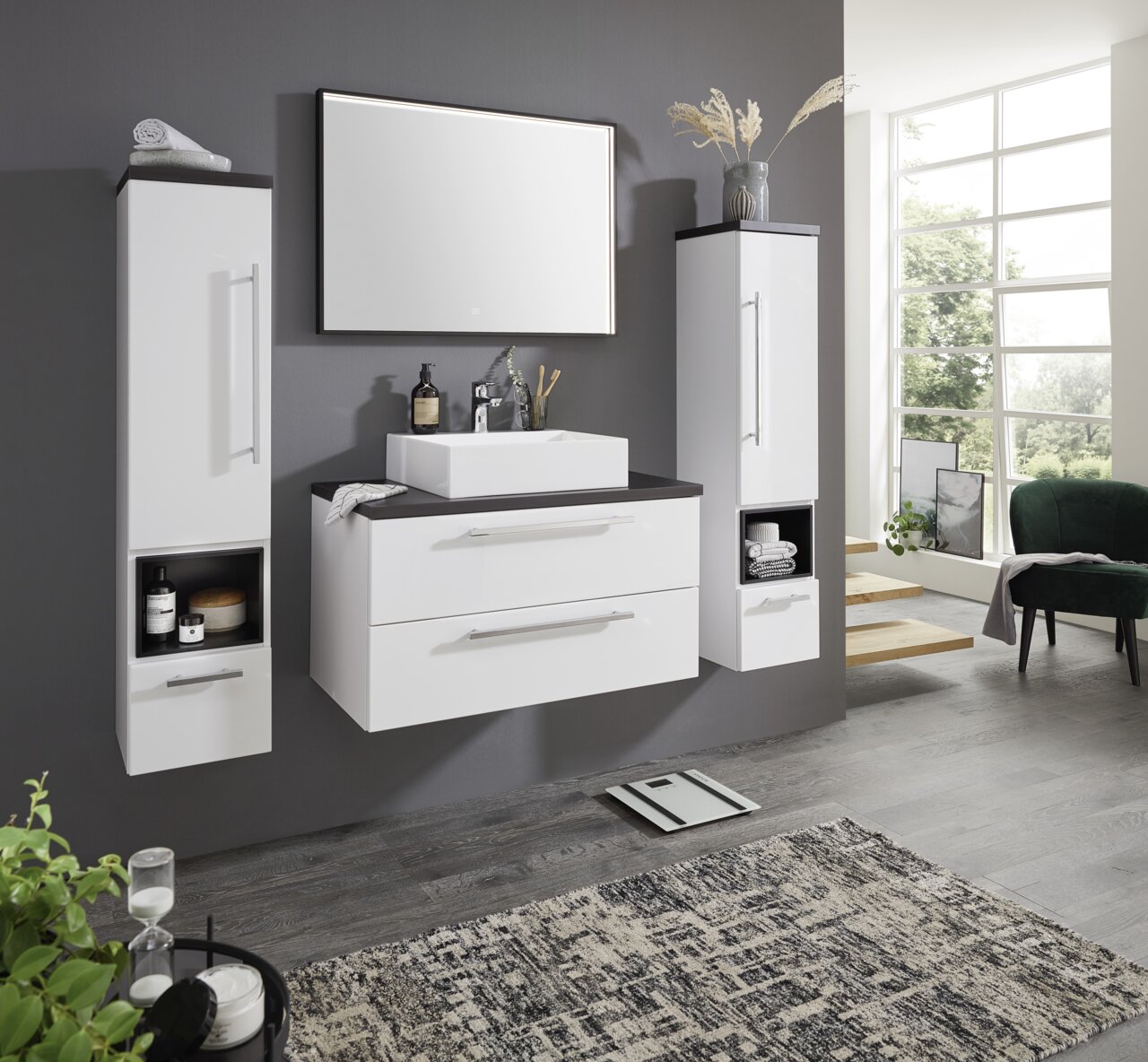 Moderne Badkombination mit weißem Waschtisch, zwei hohen Schränken und großem Spiegel, seitliche Perspektive.