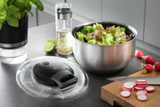 Salatschleuder PULLIT aus Edelstahl mit frischem Salat, abnehmbarem Deckel im Vordergrund, seitliche Perspektive.